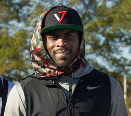 Michael Vick in a black jacket and cap poses for a picture.